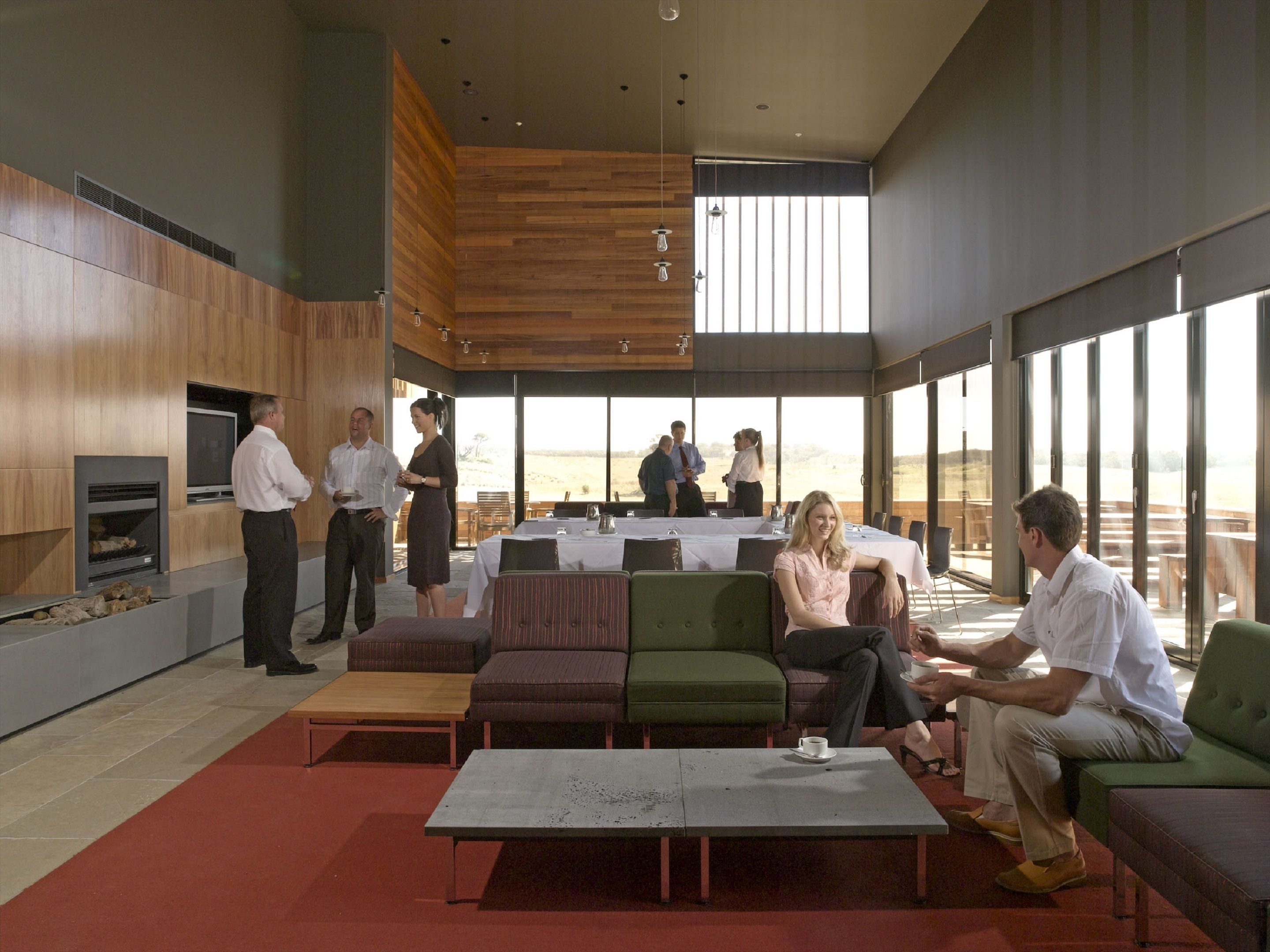 A modern indoor space with a fireplace, seating areas, and large windows offering a view.