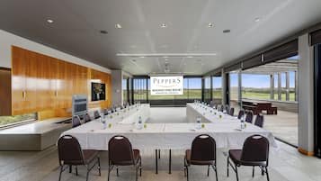 A conference room at Peppers Moonah Links Resort with a long table, chairs, and a large banner.