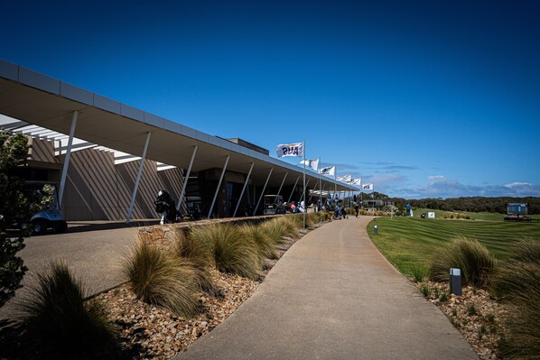 A modern building with a covered walkway and a golf course in the background.