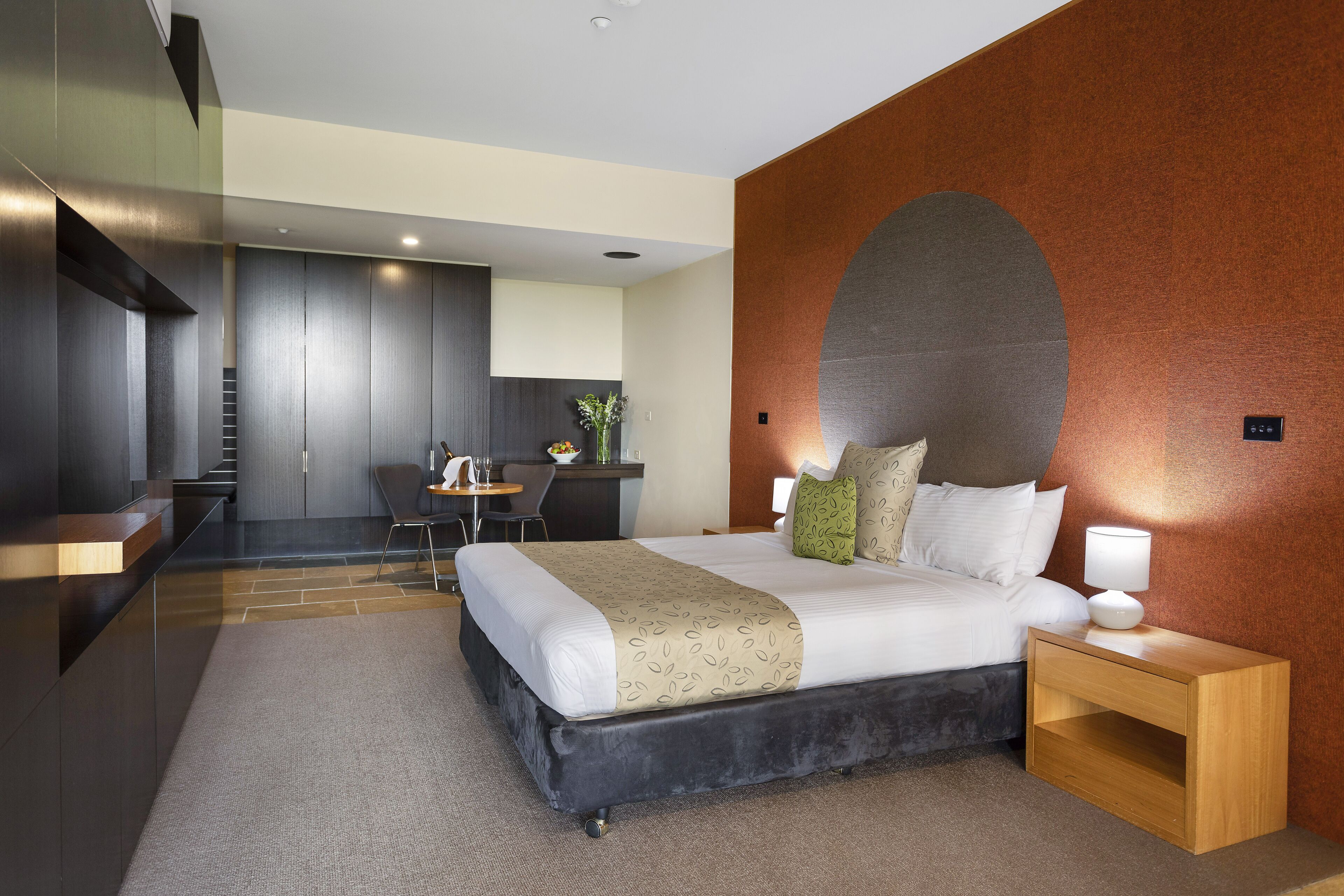 Een moderne hotelkamer met een groot bed, een houten nachtkastje, een bureau en een zithoek.