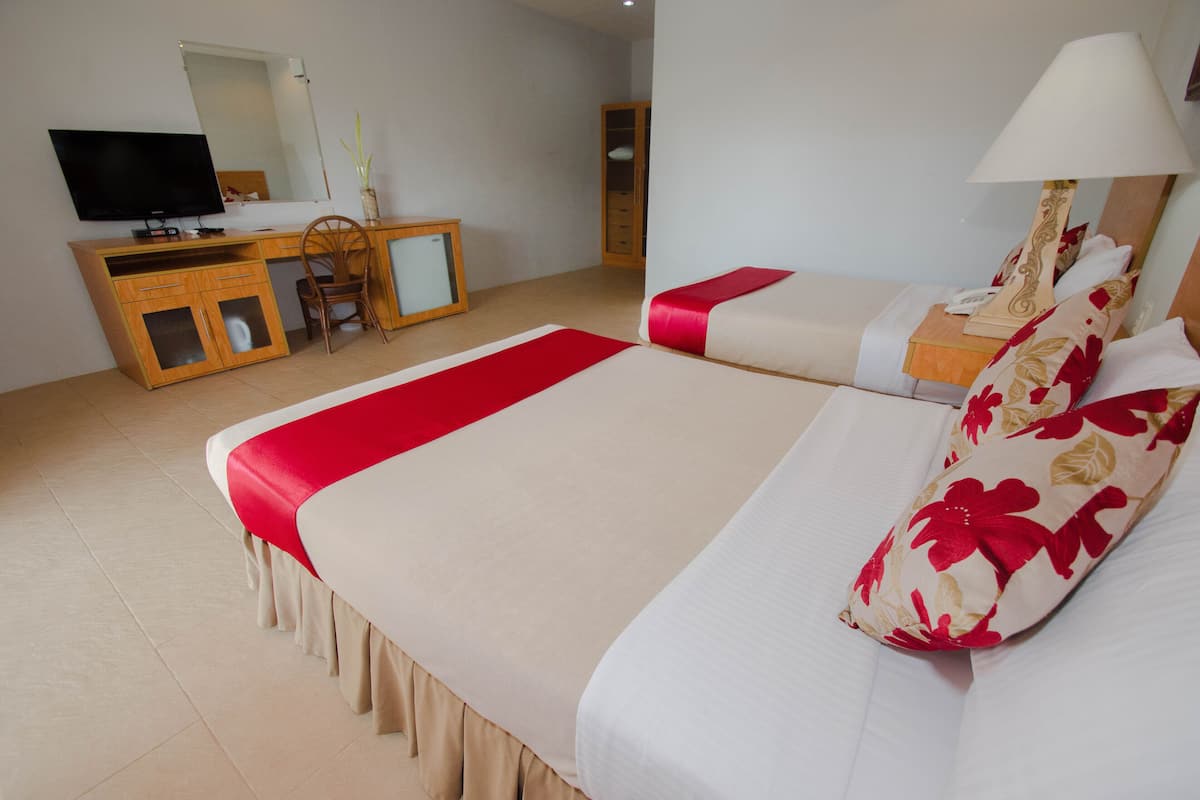 A hotel room with a bed, a desk with a television, and a cabinet.