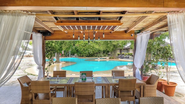 An outdoor seating area with wicker furniture, a pool, and potted plants. - Almont Inland Resort (Butuan)