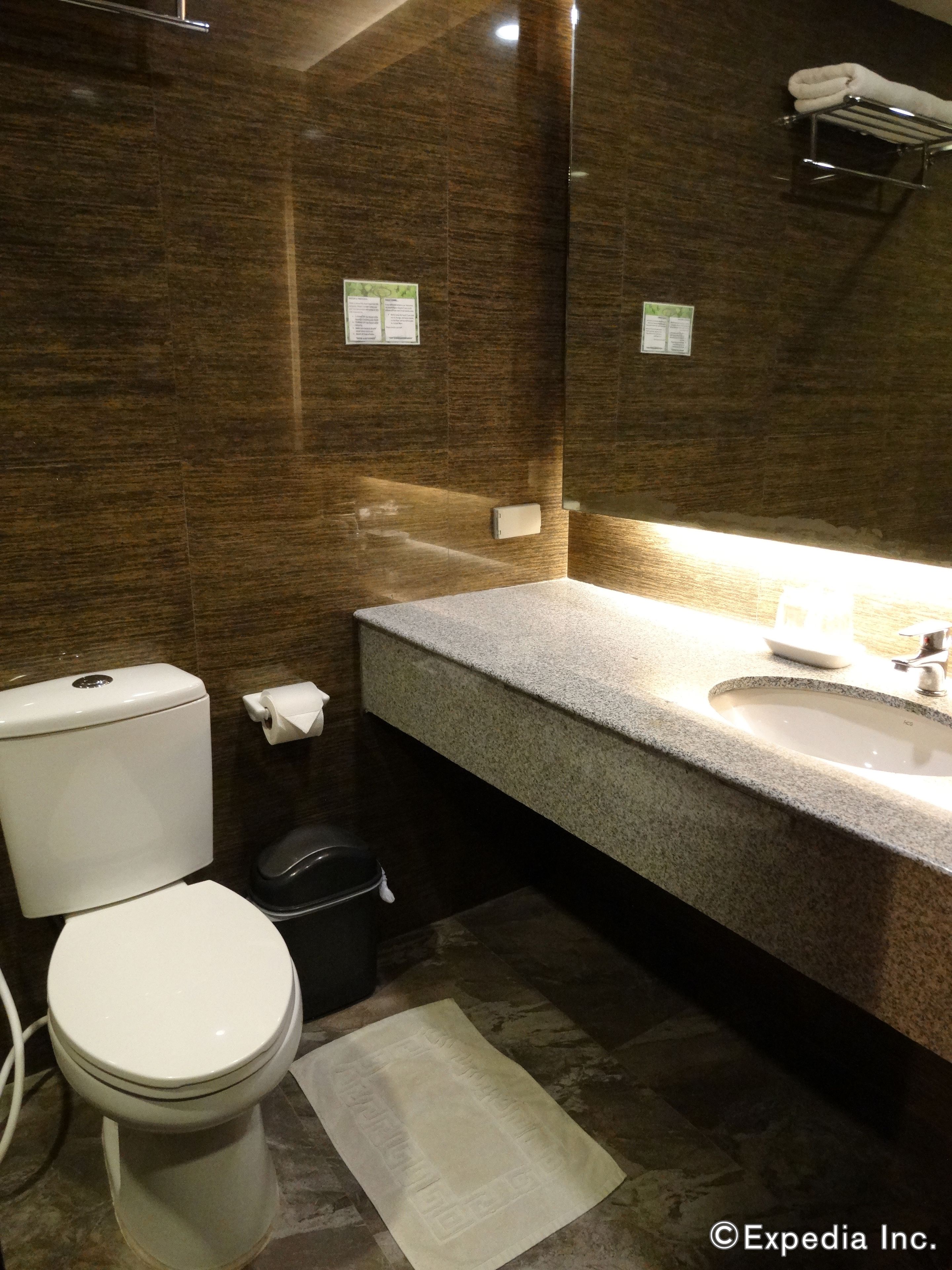A bathroom with a toilet, sink, and mirror. There are towels hanging on a rack above the sink.