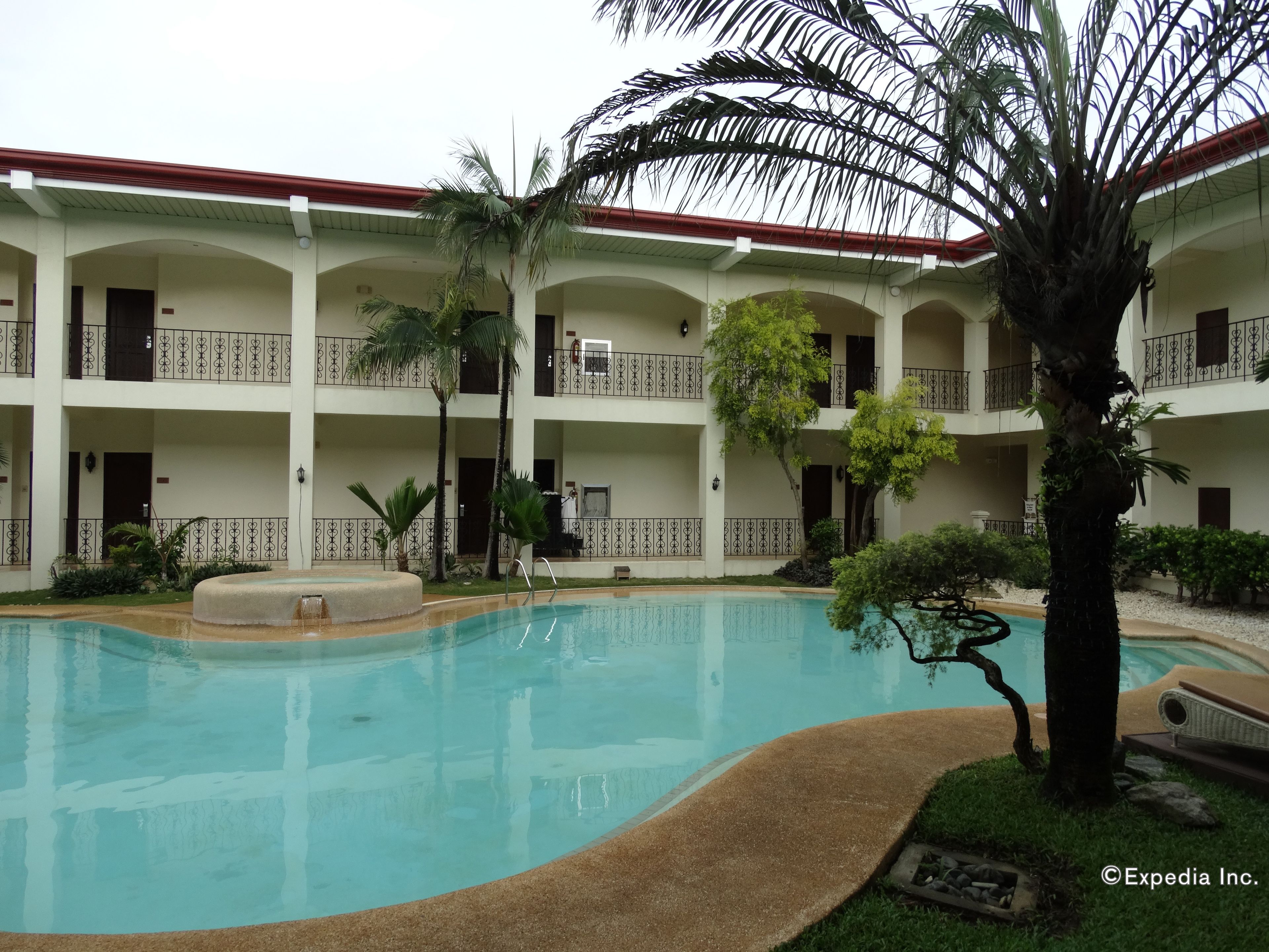 A hotel with a swimming pool, multiple balconies, and palm trees.