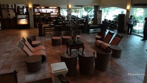 A spacious lobby with comfortable seating, a bar area, and large windows offering a view of the outdoors.