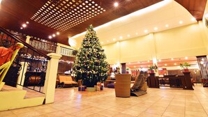 A spacious lobby with a large Christmas tree, comfortable seating, and a modern ceiling design.