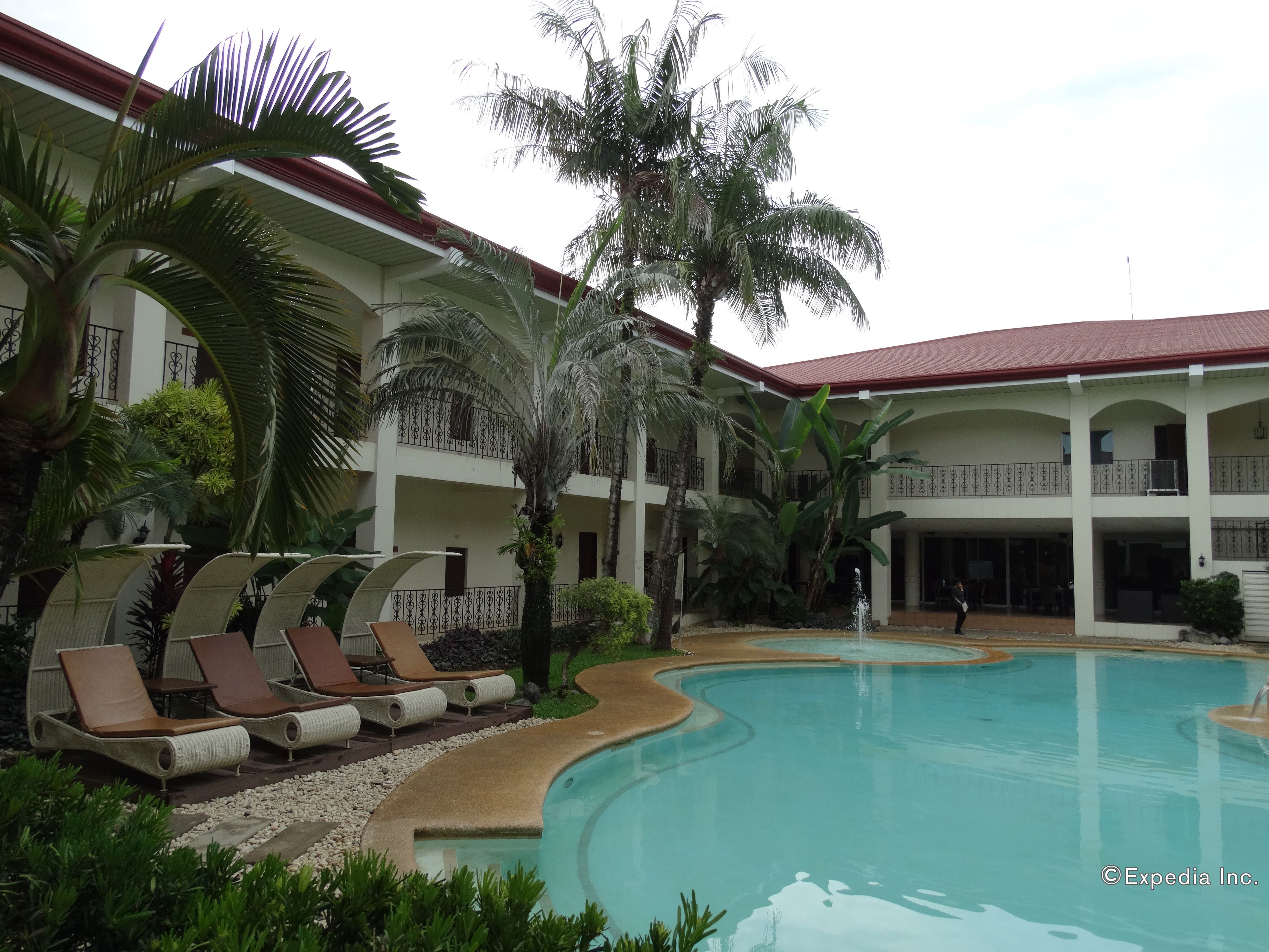 A pool area with lounge chairs and palm trees.