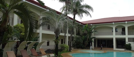 A pool area with lounge chairs and palm trees.