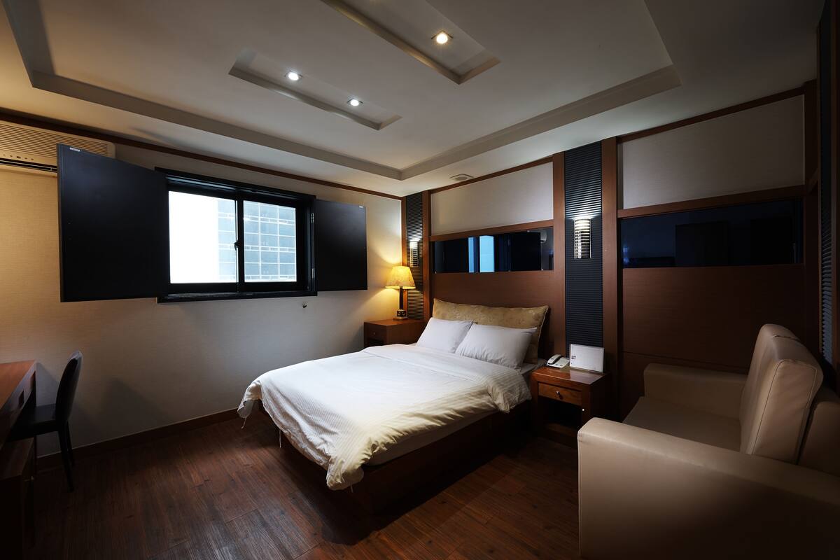 Una habitación de hotel moderna con una cama grande, un escritorio, una silla y un sofá.