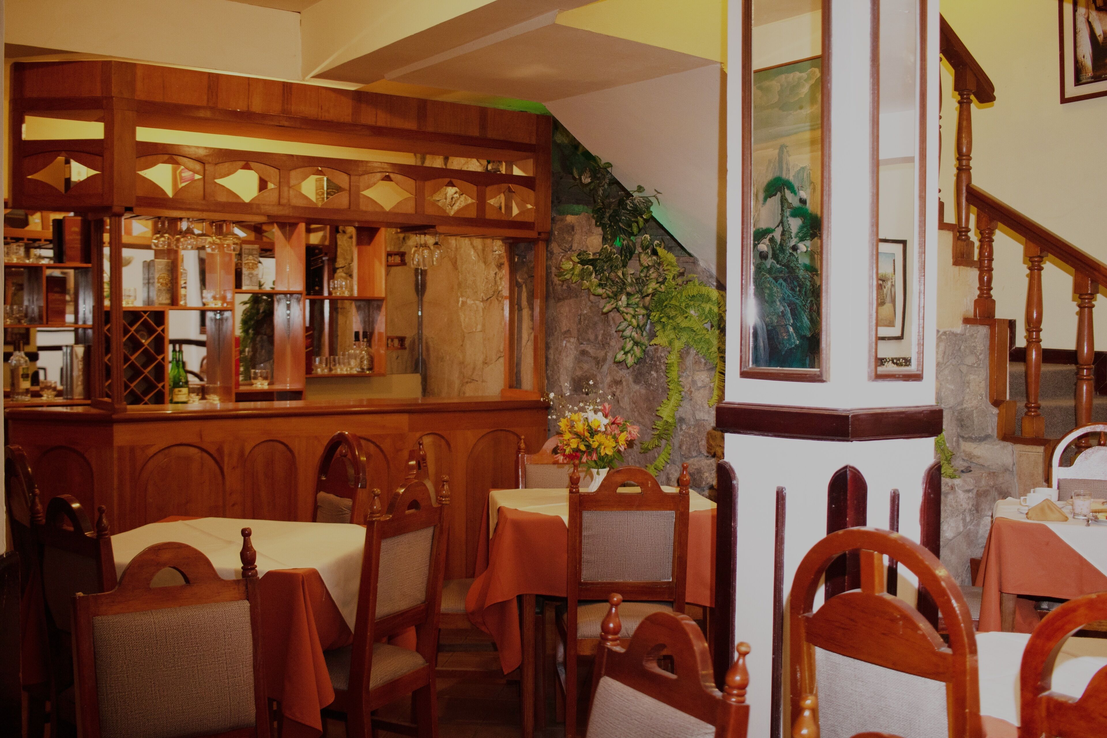 Ein Restaurantinneres mit Holzkubaturen, einer Bar und einer Treppe.