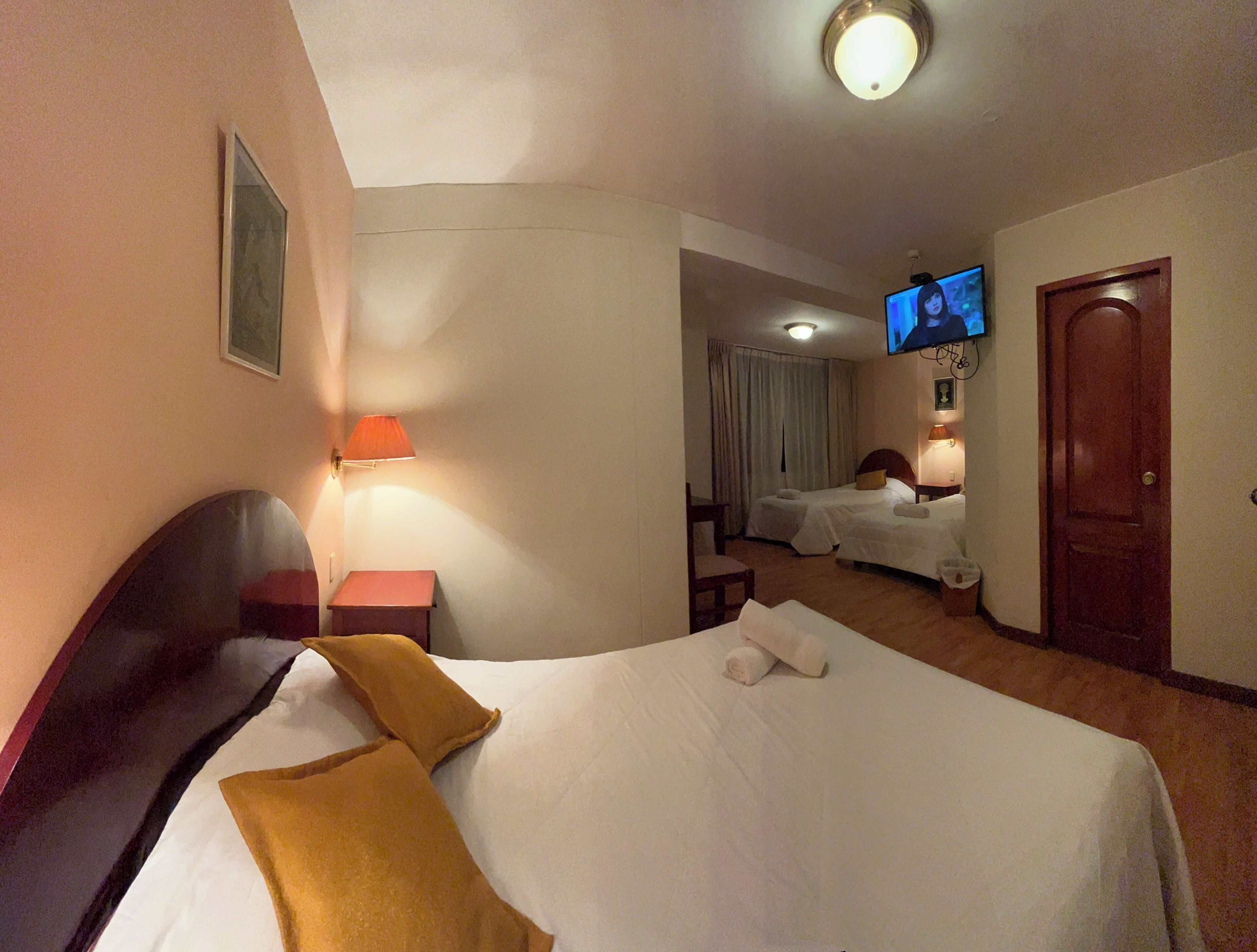 A hotel room with a bed, a TV, a desk, and a chair.