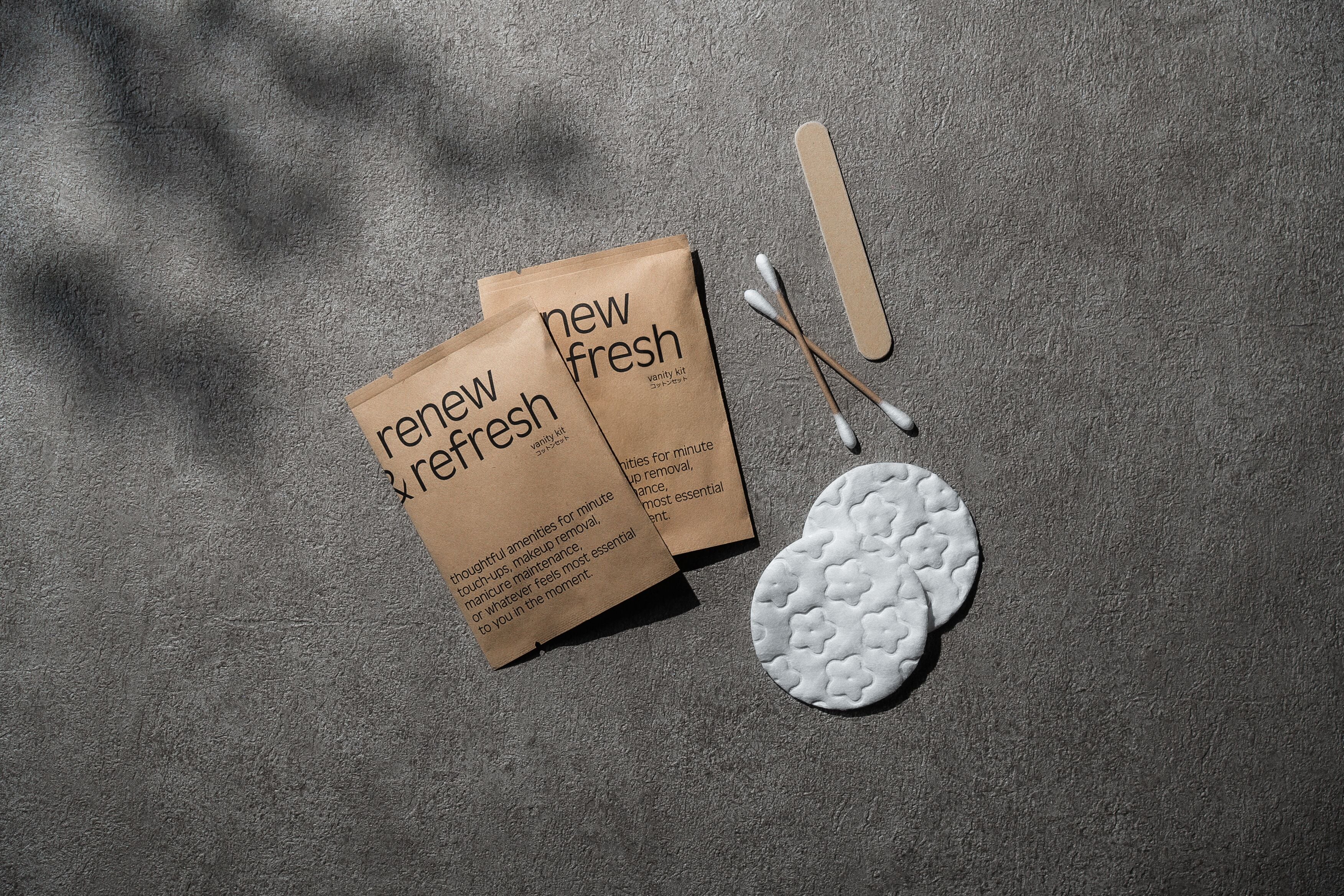Duas sacolas de papel castanho com a inscrição 'novo e fresco', contendo cotonetes e um objeto circular branco sobre uma superfície texturizada.