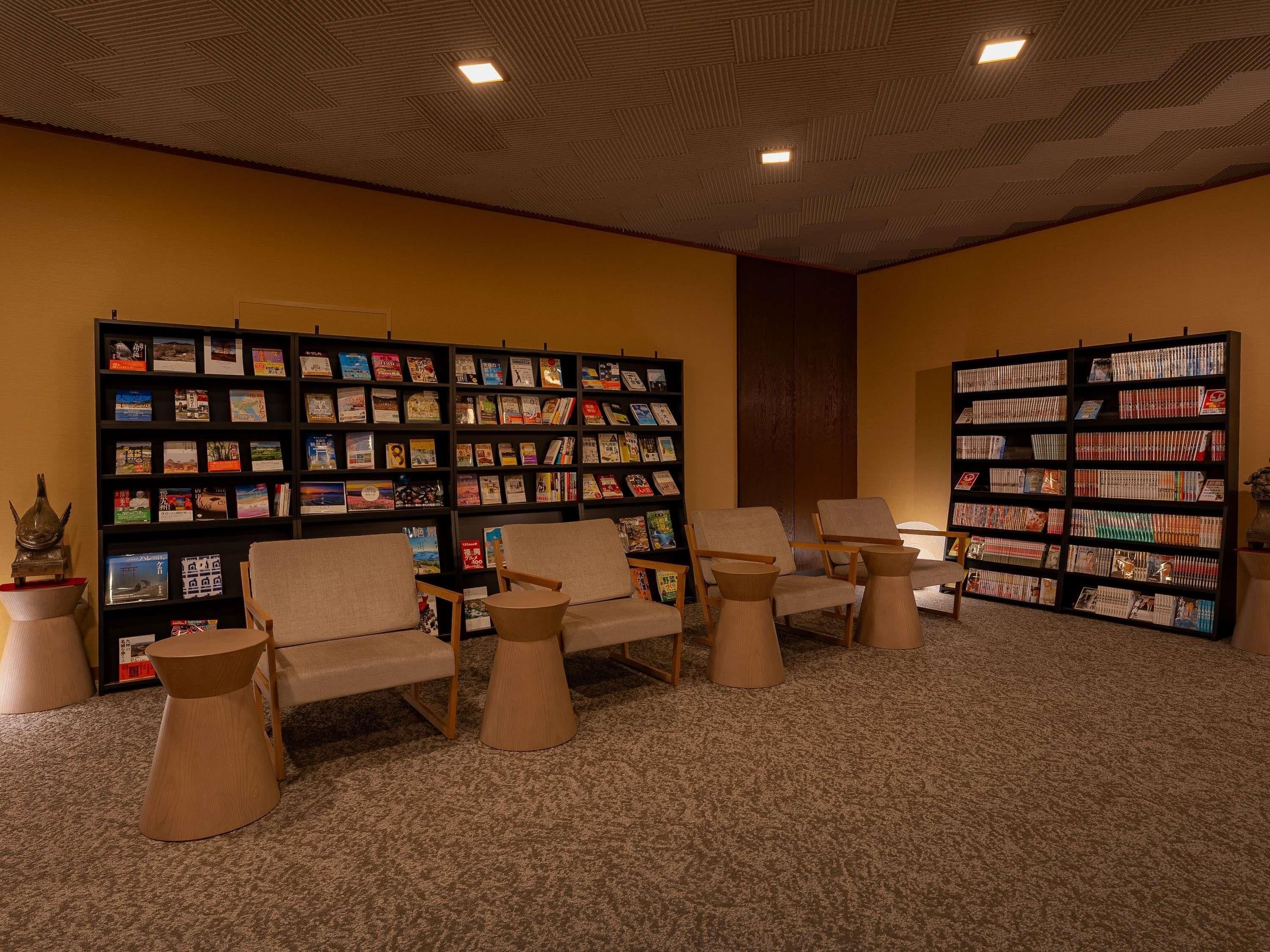 Een leeshoek met boekenkasten, stoelen en een vloerkleed.
