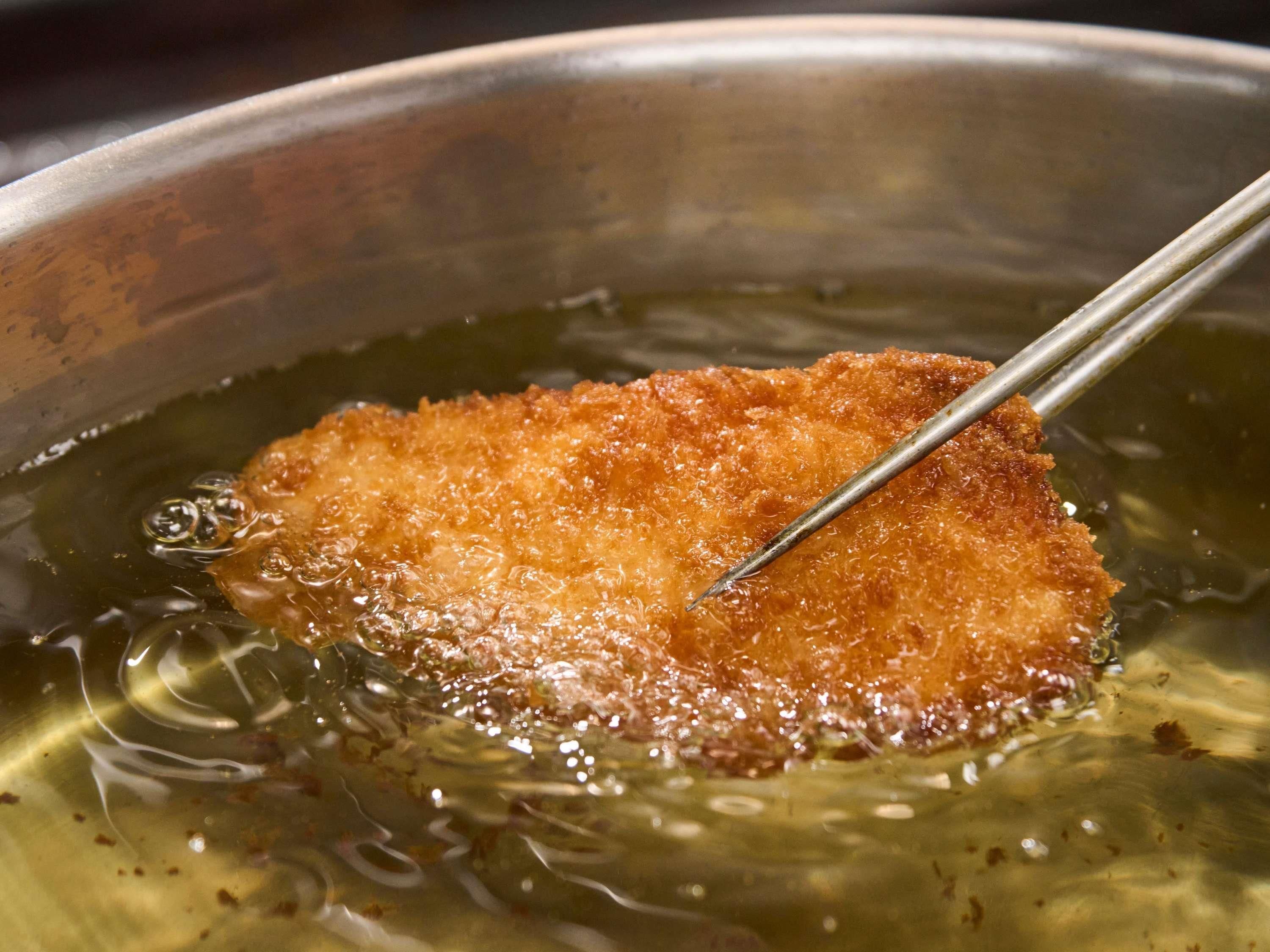 A close-up of a food item being fried in oil.