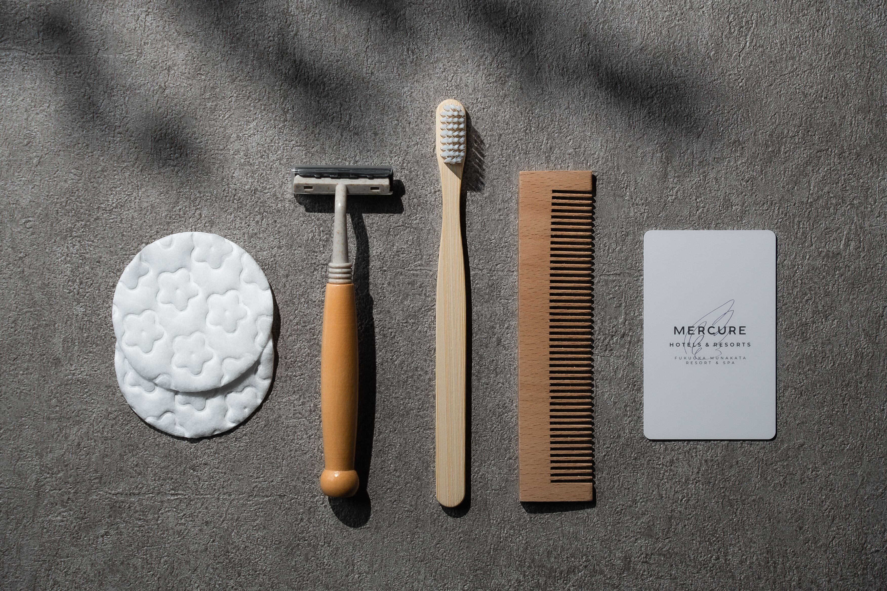 A comb, a toothbrush, a razor, a soap, and a Mercure hotel card on a textured surface.