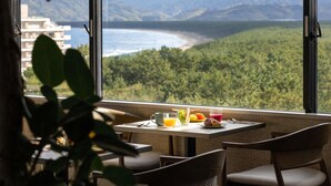 A dining area with a table set for two, overlooking a mountainous landscape and a body of water. - Mercure Saga Karatsu Resort (Karatsu)