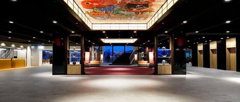 Eine geräumige Lobby mit hoher Decke und einem großen, farbenfrohen Wandgemälde.