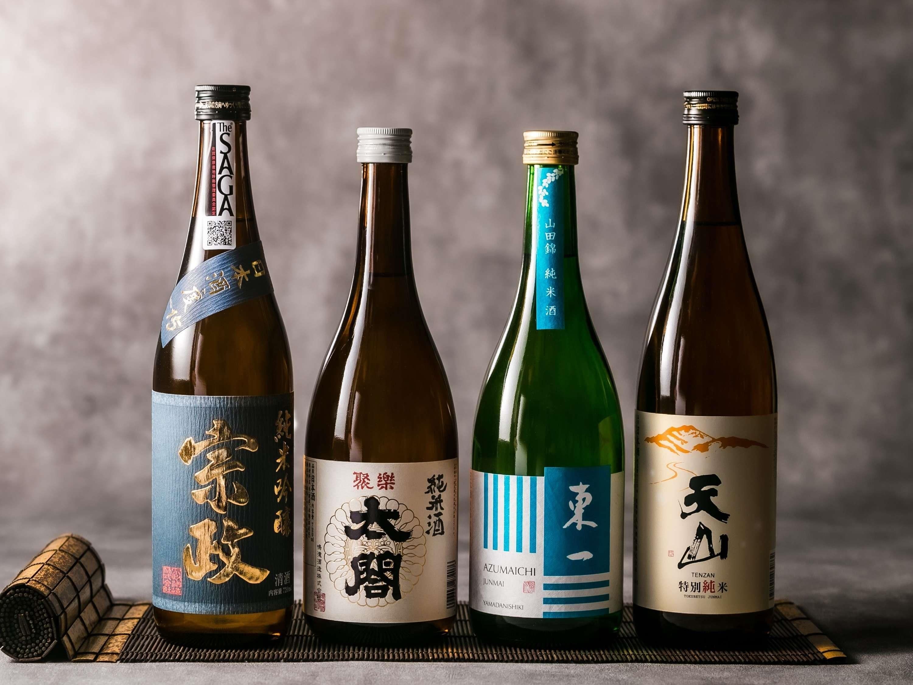 Four bottles of sake with labels, placed on a mat.
