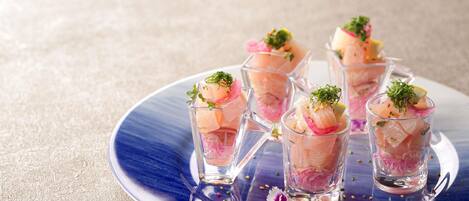 A blue plate with clear glasses containing a pinkish food item, garnished with green herbs and a flower.