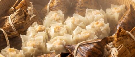Una vaporera de bambú con dumplings envueltos en hojas.