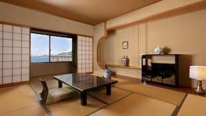A traditional Japanese room with tatami flooring, a low table, a sofa, a fireplace, and a view of the sea. - Mercure Saga Karatsu Resort (Karatsu)