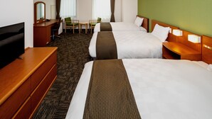 Ein Hotelzimmer mit zwei Betten, einem Schreibtisch, einem Fernseher und einer Wand in Grünton.
