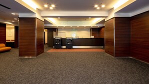 Eine moderne Hotelhalle mit einer Rezeption, zwei schwarzen Faxgeräten und einem Teppichboden.