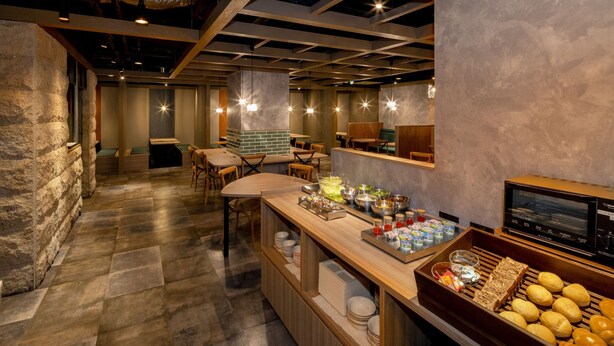 Ein Restaurant mit einer Steinwand, Holztischen und einer Buffettheke mit Brot und Beilagen.