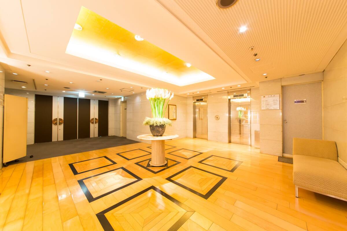 A hotel lobby with a central floral arrangement, a reception desk, and a seating area.