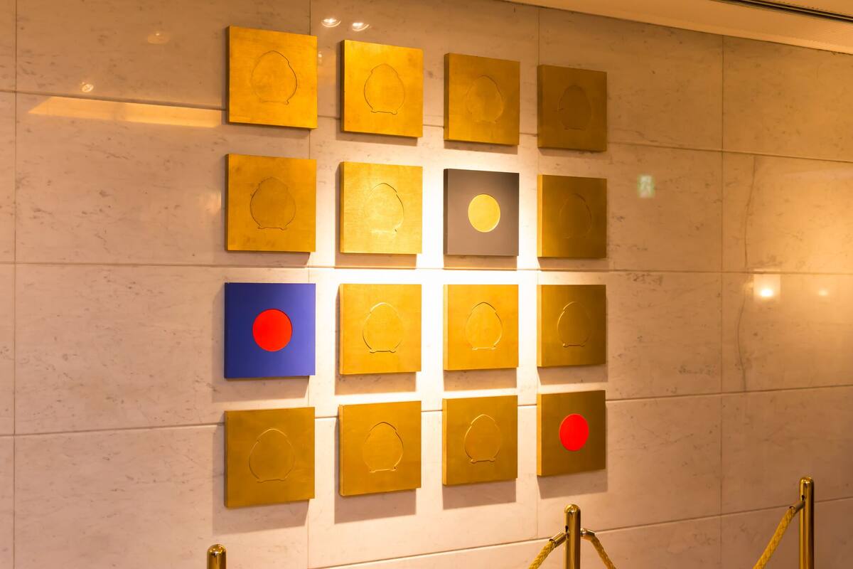 A wall with multiple square plaques, some with circular cutouts, arranged in a grid pattern.