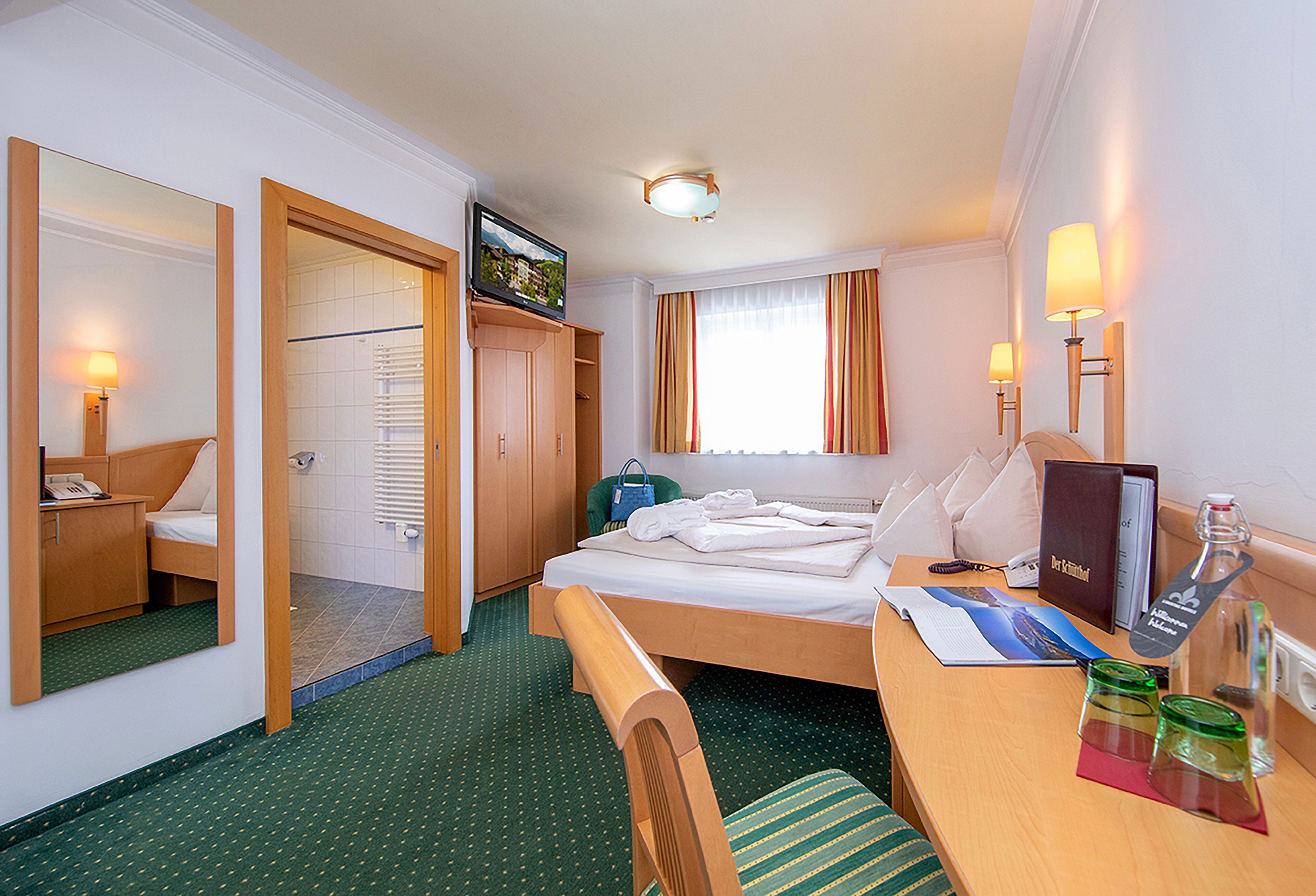 Ein Hotelzimmer mit Bett, Schreibtisch, Stuhl, Fernseher und Bad.