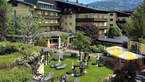 A hotel with multiple balconies, a chapel, and a view of mountains. - Hotel Der Schütthof (Zell am See)