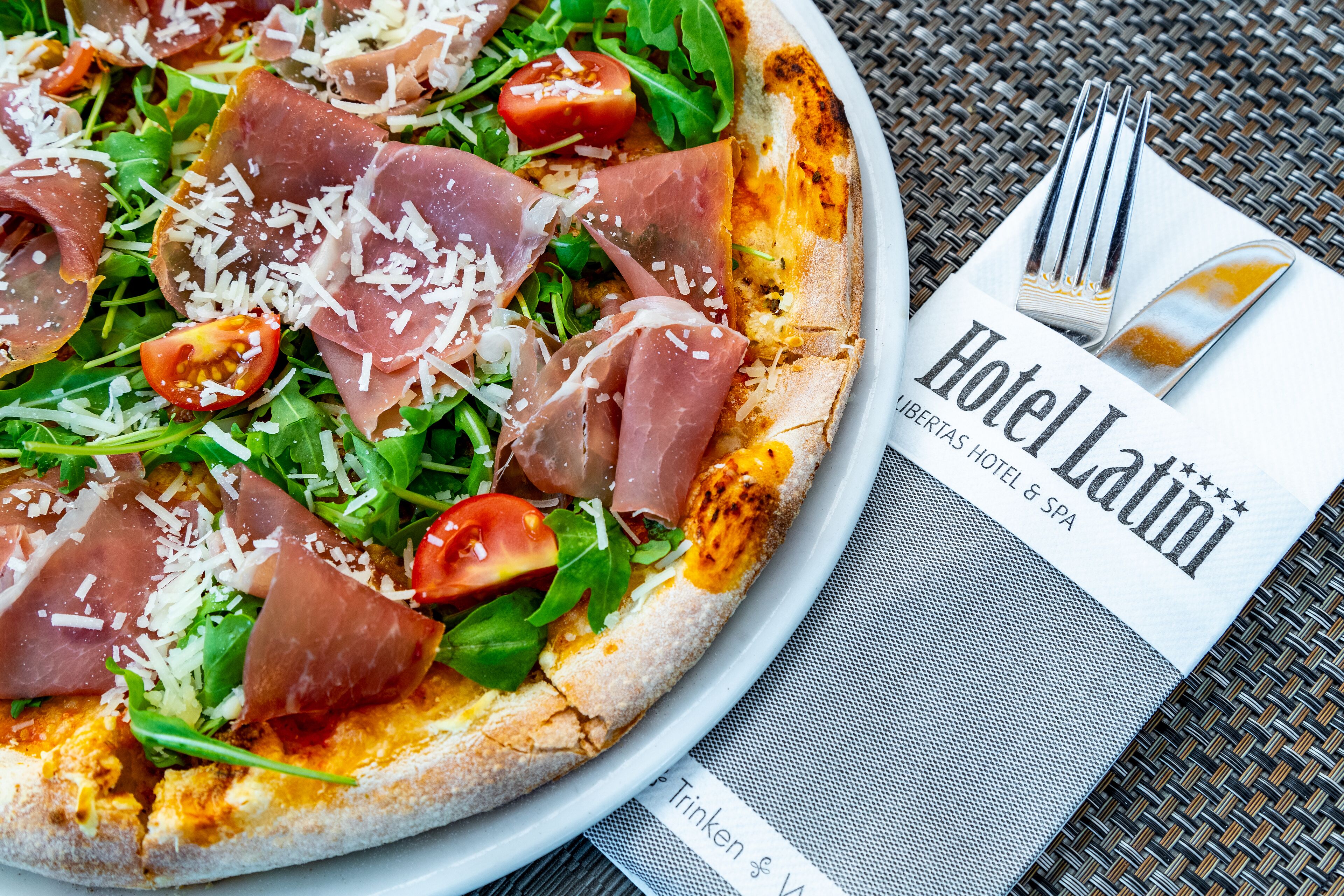 A pizza with various toppings, a fork, and a napkin with a hotel name.