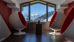 A room with two red and white chairs facing a large window with a mountain view. - Hotel Der Schütthof (Zell am See)