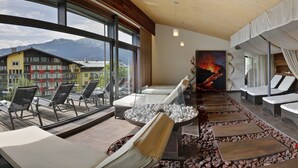 A modern lounge area with a view of mountains, outdoor seating, and a unique art piece. - Hotel Der Schütthof (Zell am See)