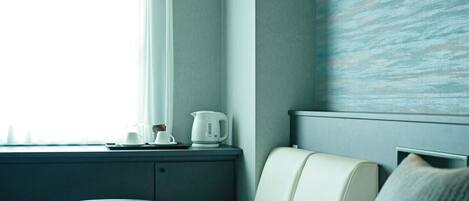 Habitación de hotel con cama, una mesita redonda, ventana con cortinas, radiador fijado a la pared y pared con textura.