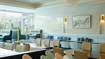 Un hall d’hôtel moderne, doté d’espaces aménagés avec des sièges, d’un comptoir de réception et d’une grande fenêtre donnant sur l’extérieur.