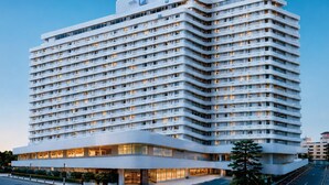 Un hotel de varios pisos con fachada plana, numerosas ventanas y una entrada destacada con puertas de vidrio.
