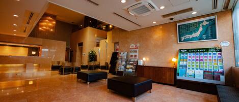 A spacious lobby with a reception desk, seating area, and a large wall display.