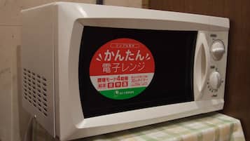 Eine Mikrowelle mit japanischem Text auf dem Bildschirm, auf einem Tisch mit kariertem Tischläufer platziert.
