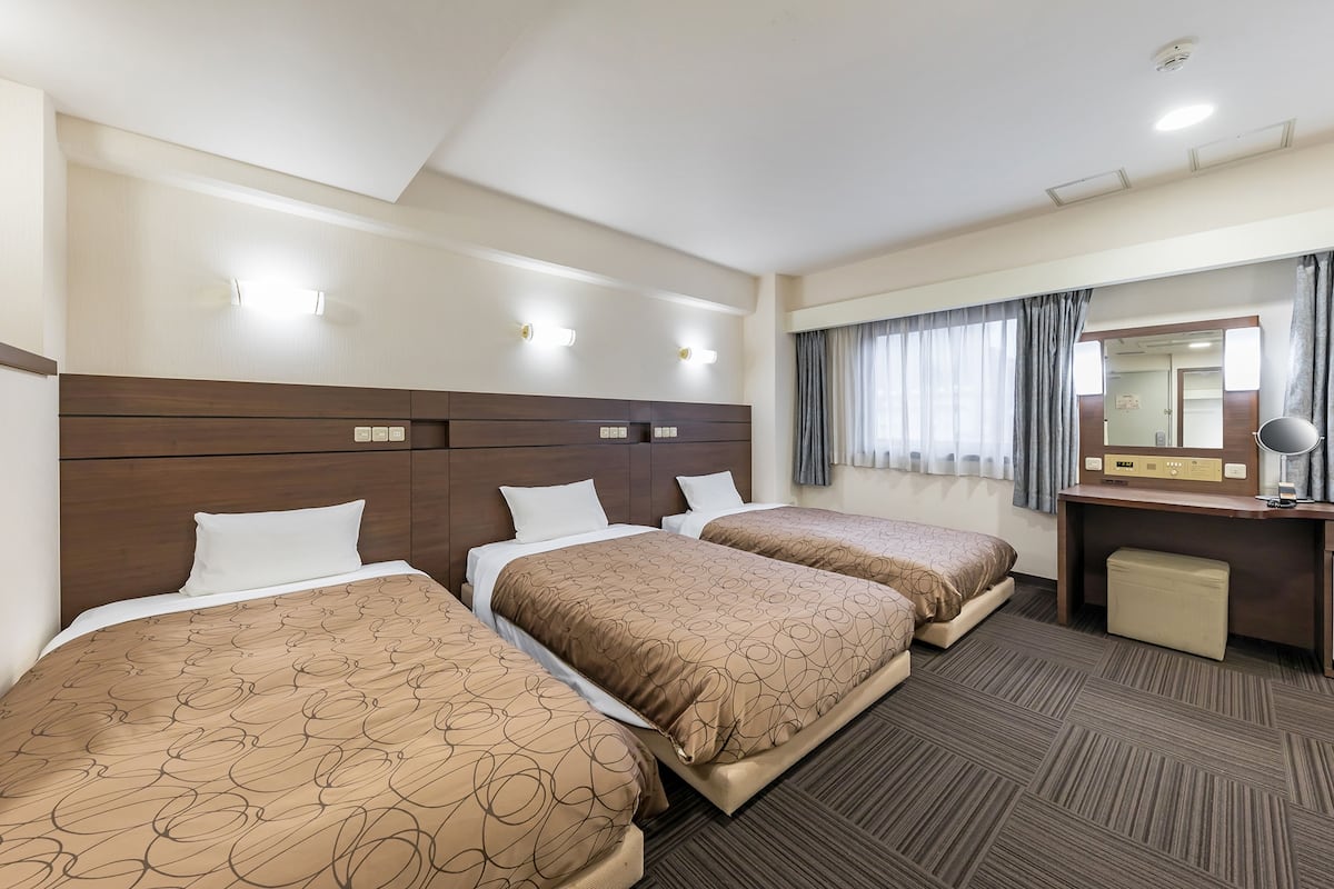 Habitación de hotel con dos camas, un escritorio, una silla y un espejo.
