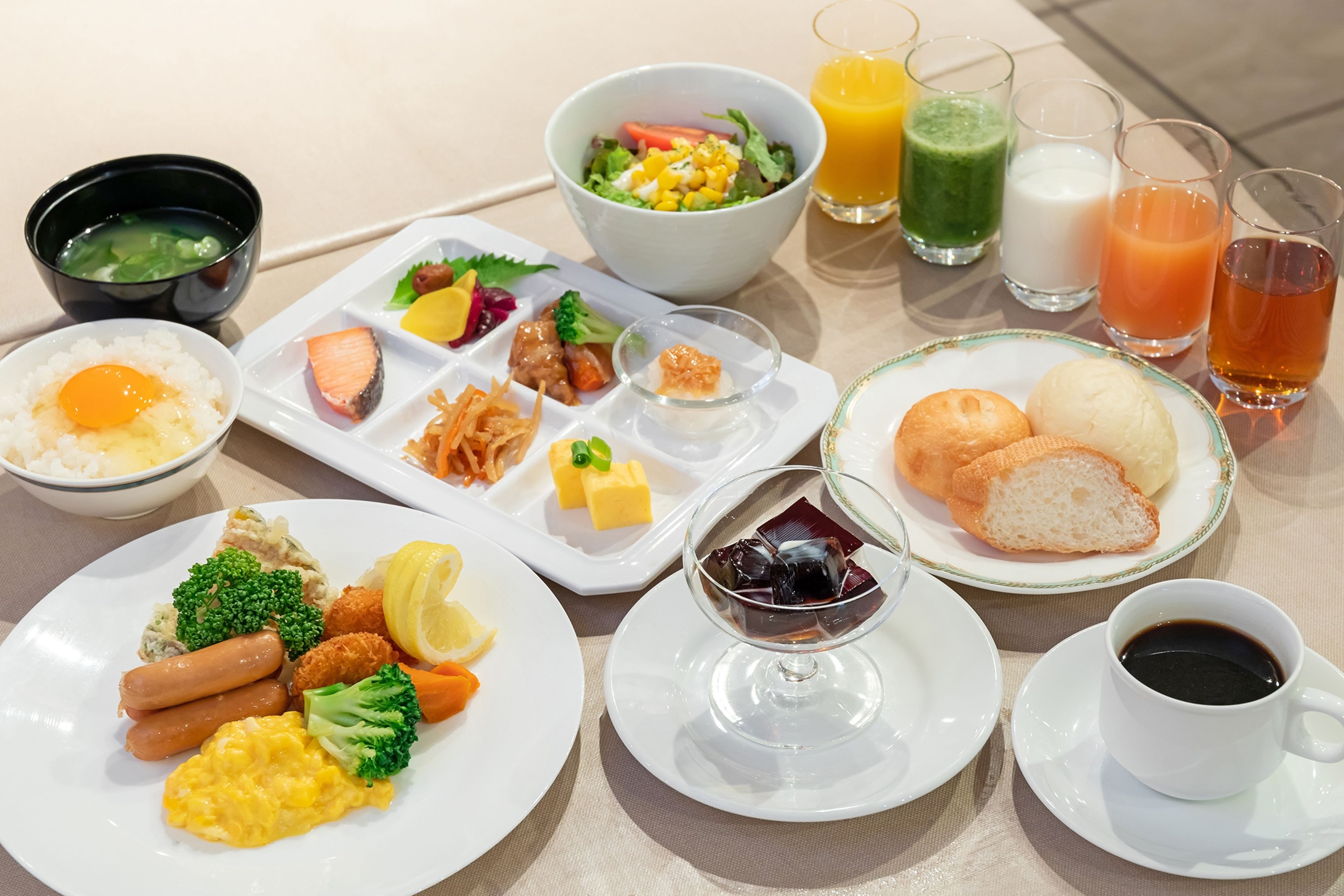 A breakfast buffet with various dishes, drinks, and a cup of coffee.