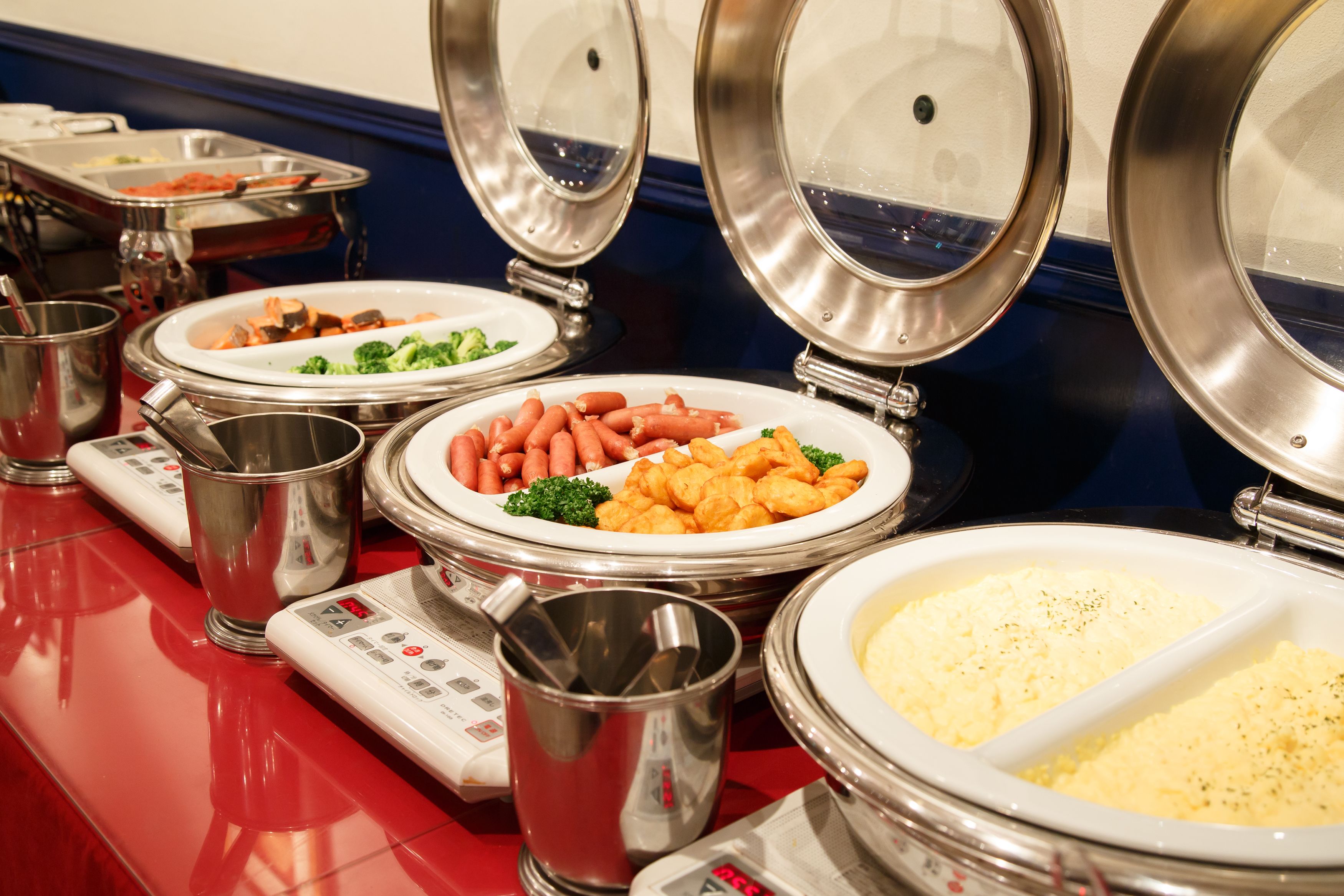 A buffet setup with various food items and serving utensils.
