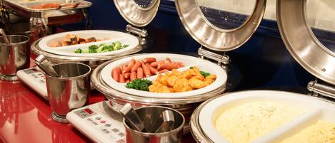 A buffet setup with various food items and serving utensils.