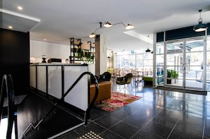 A modern hotel lobby with a reception desk, seating area, and large windows offering views.