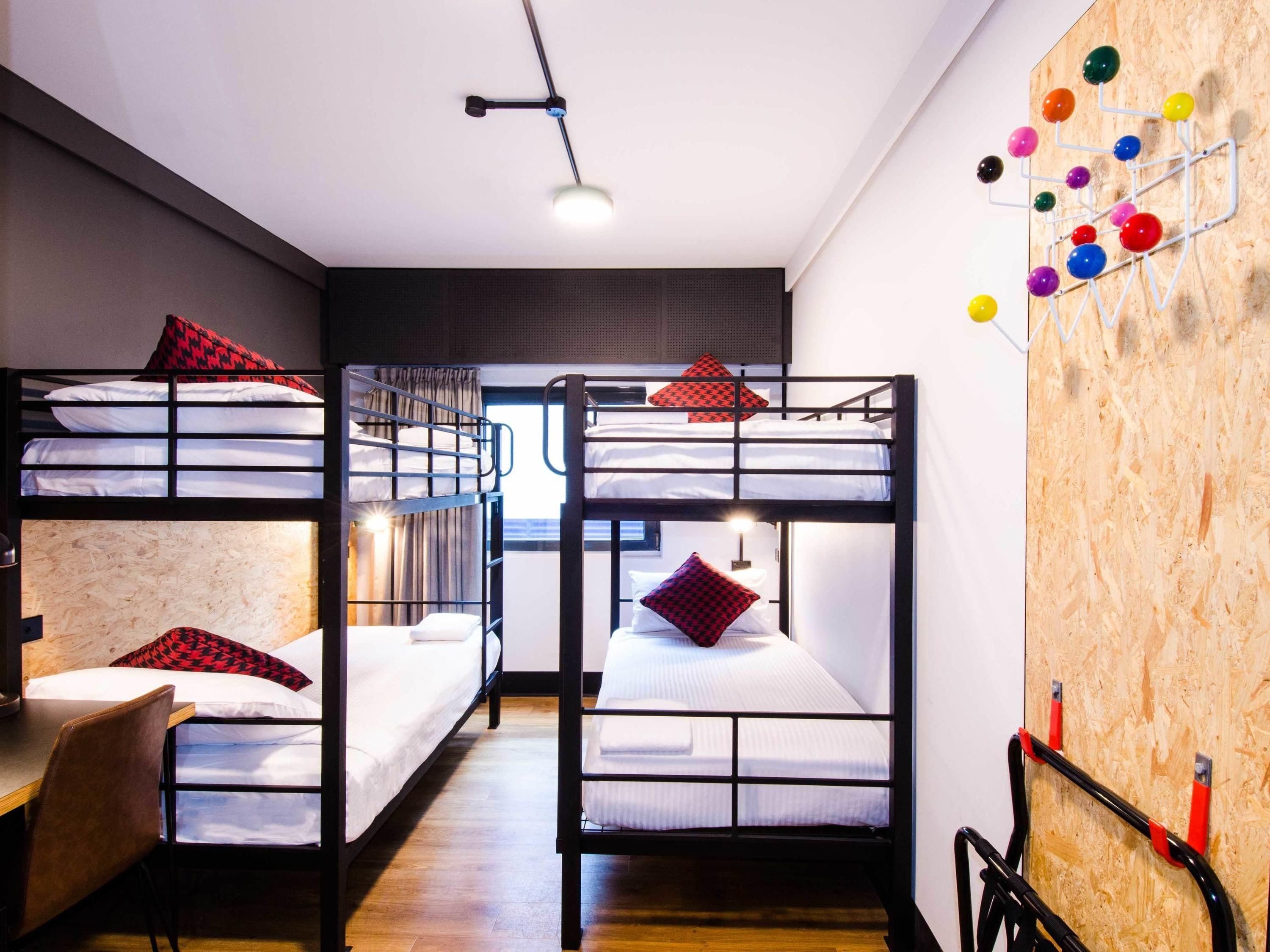 A bunk bed room with a desk and chair, a wooden wall with a pegboard, and a hanging light fixture.