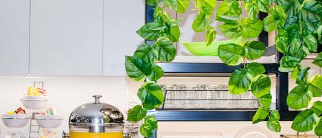 Una encimera de cocina con una cafetera, tazones y una planta colgante.