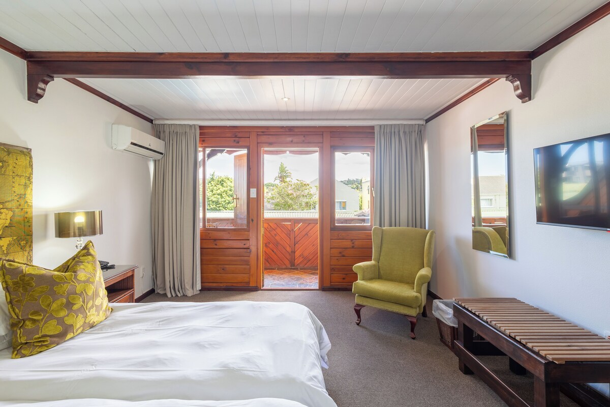 Una habitación de hotel con una cama, una silla, un escritorio y un televisor.