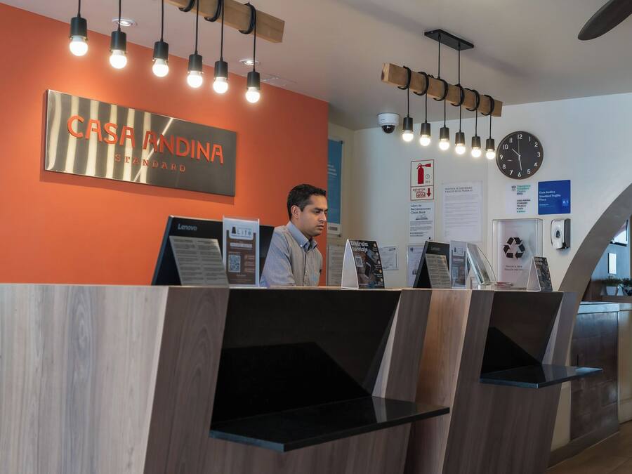 A reception desk with a sign reading "CASA ANDINA STANDARD" and a clock on the wall.