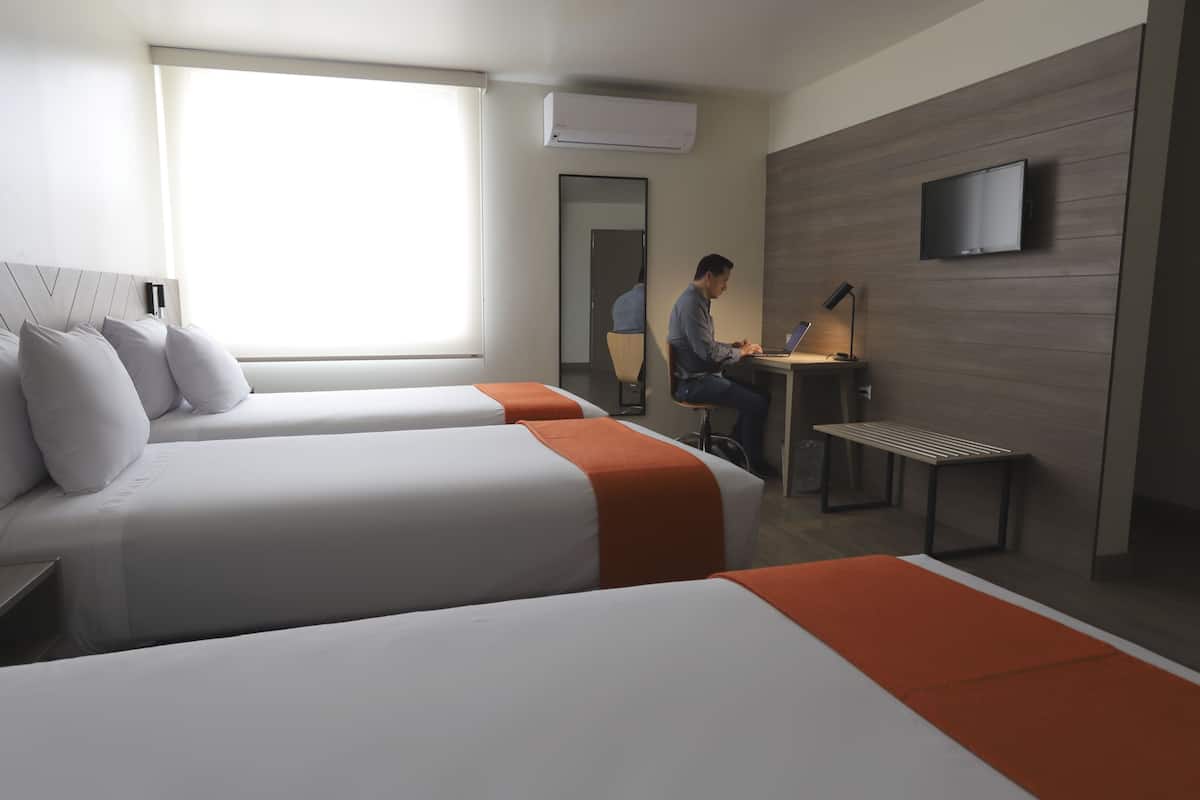 Une chambre d’hôtel avec deux lits, un bureau, une chaise, une télévision et un appareil de climatisation.